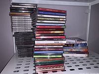 Large mixed pile of over 50 CDs stacked vertically and horizontally with some DVDs.