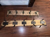 Both wooden coat racks side by side on wood floor, showing metal hooks and general condition