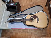 Natural wood Yamaha EF-31 acoustic guitar in open hard shell case on parquet floor