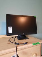 Front view of HP ProDisplay P232 monitor powered off showing screen and attached black cable on wooden surface.