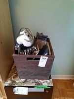 Wooden crate on top of a floral-patterned box containing a Canon calculator, several binders, notebooks and a Casio EZ label printer without cord.