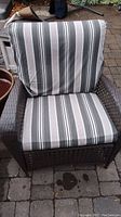 Front view of the faux wicker patio chair with gray, white, and black striped cushions on seat and backrest.