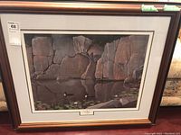 Framed print showing rocks with a water bird and lily pads, with matting and wood frame.