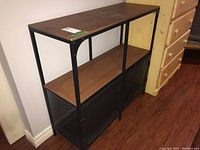 Front view showing metal frame, laminate shelves, and two-door lower cabinet with perforated metal panels.