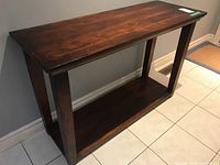 Front angled view of wood veneer console table showing rectangular top and lower shelf, with visible crack on the top edge.