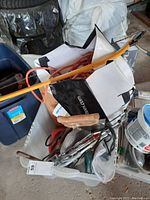Bin with assorted tools including hand saws, extension cords, and sandpaper