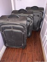 Three black Travelpro rolling suitcases lined up, showing exterior front and top handles