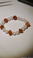 Photo showing the stretchy bracelet made of alternating round light rose quartz beads and rounded square orange-brown carnelian beads.