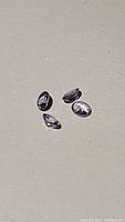 Four natural blue-purple tanzanite gemstones shown in close-up on a neutral background, showcasing color and clarity.