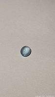 Light blue oval cabochon aquamarine stone displaying catseye effect against neutral background.