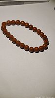 Full view of stretchy bracelet composed of round red jasper beads laid flat on a white surface.