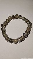 Natural smokey quartz bead bracelet arranged in circle showing bead size and color.