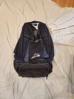 Top and front view of the black Alias moto gear bag showing logos and zipper compartments
