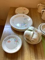 Full view of grouped plates and cups on wood surface showing set completeness and floral design.