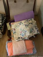 Top view of floral fabric, lavender and orange colored fabrics stacked and folded inside vintage brown suitcase.