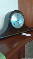 Side view of wooden tambour style mantle clock on a wooden surface