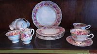 Full display of tea service showing cups, saucers, plates, cream jug and sugar bowl on shelf.