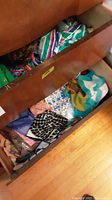 Two wooden drawers filled with assorted ladies scarves in varied colors and patterns including stripes, polka dots, floral, and animal prints.