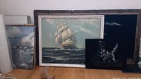 All three framed artworks together, showing large ship painting, framed velvet dog painting, and framed velvet ship painting on black background.