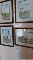 All four framed watercolours arranged on a wall, showing rural landscape scenes with houses and nature.