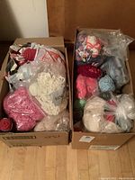Photo of two cardboard boxes filled with assorted wool yarn skeins and balls in various colors and packaging.