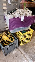 Plastic tub with white cords on top, gray and yellow crates underneath with various cords and devices.