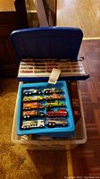 Top view of Hot Wheels cars in blue plastic case and additional item box underneath.