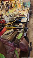 Wide view of workbench showing red Craftsman bench vise, assorted hand tools, and workshop accessories laid out