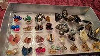 Full view of approximately 26 pairs of retro style costume jewelry earrings in plastic tray, showcasing a variety of bead, stone, metal, and artisan styles in different colors and shapes.