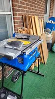 Full view of table saw on fold-and-roll stand with wood remnants behind