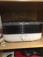 Front view of the Ronco EZ-Store Turbo 5-Tray food dehydrator with temperature control dial and 5 tray compartments visible under a clear lid.