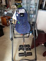 Full view of blue Teeter Hang Ups inversion table showing backrest with ventilation slots, arm handles, ankle supports, and frame.
