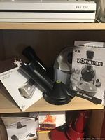 Dole Yonanas ice cream maker parts with user manual and Wolfgang Puck sharpener manual on a shelf