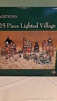 Photo of the original box showing the complete 25 piece lighted Christmas village set by Traditions.
