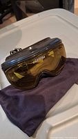 Carrera Vision Supergold ski goggles resting on a soft dark-colored lens cleaning bag on a plastic surface.