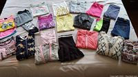 Photo showing all clothing items laid out on a bed, including cardigans, tops, pants, and skirts.