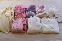 Full view of all dress up clothes laid out showing various colors and fabrics including gold, pink, white, and purple dresses and tops with accessories.