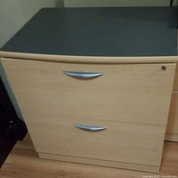Front view of natural maple color filing cabinet with two drawers, silver handles, lock on top drawer.