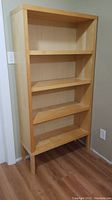 Front view of the IKEA Agerum bookcase showing all four fixed shelves and natural birch veneer finish.