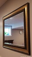 Large rectangular wall mirror hanging on beige wall, showing reflection of room interior.