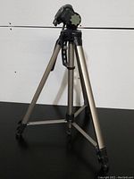 Full view of Optex OPT455 tripod standing open, showing three aluminum legs with black rubber feet, black pan head, and carrying handle.