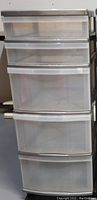 Front view of the plastic storage cart showing five transparent drawers stacked vertically with white handles.