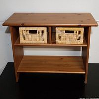 Front view of solid pine side table with two wicker baskets in upper compartments.