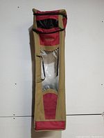 Full view of Rubbermaid wrapping paper organizer showing tan and red fabric with clear plastic window panel and strap on one side.