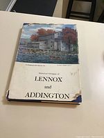 Front cover of the hardcover book with a color image of a historic mill by river and the title 'Historical Glimpses of Lennox and Addington'. Shows wear and corner damage on jacket.