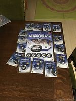 Photo showing the large display card for the Toronto Maple Leafs Mini Puck Collection surrounded by unopened individual mini puck packages.