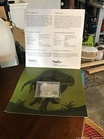 Photo showing the coin in packaging on certificate of authenticity with T. rex illustration.