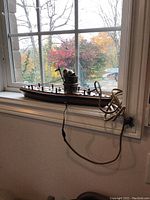 Full side view of the 18-inch vintage battleship nightlight on a window ledge with visible old electrical cord and switch.