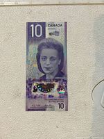 Front of a crisp purple Canadian $10 banknote showing a portrait of Viola Desmond and holographic security features.