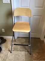 Front view of director's style fold-up chair showing the wood seat and backrest with metal frame and footrest.